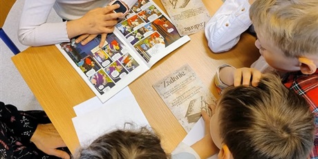 Powiększ grafikę: uczniowie klasy 1 czytają wskazówki do zadania